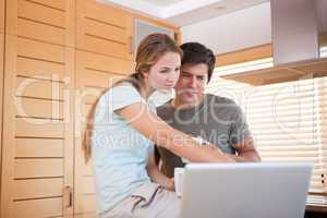 Woman pointing at laptop screen by man