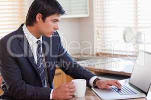 Business man using laptop while having coffee
