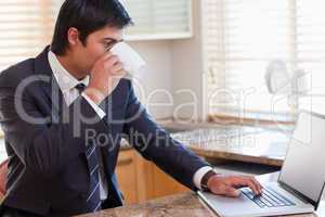 Business man using laptop while drinking coffee
