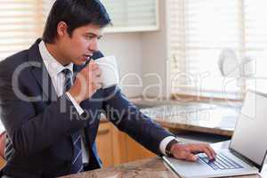Business man using laptop while drinking coffee