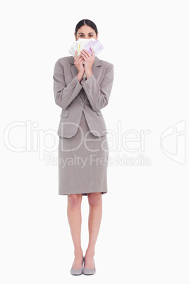 Business woman holding fanned banknotes in front of face