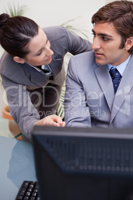 Colleagues in discussion while using computer at office
