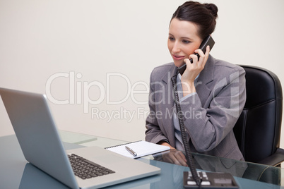Business woman using laptop while on call