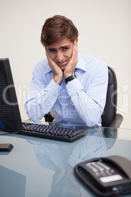 Young worried business man sitting at office desk