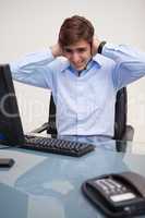 Business man covering ears at office desk