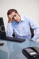 Young tense business man sitting at office desk