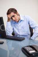 Young tense business man sitting at office desk