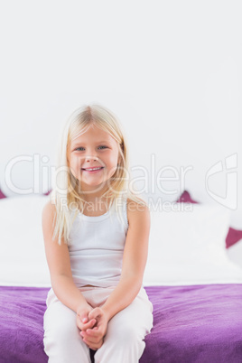 Little girl sitting on a double bed