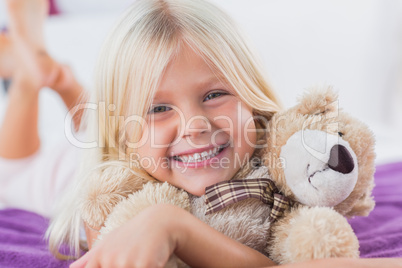 Blonde girl embracing her teddy bear