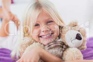 Blonde girl embracing her teddy bear