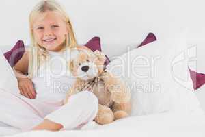 Little girl sitting near to her teddy bear