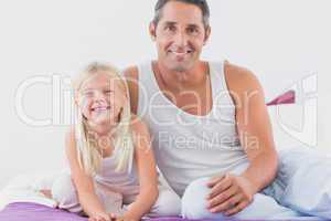 Father and his daughter sitting on a bed