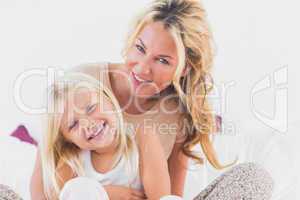 Mother and her daughter sitting on a bed