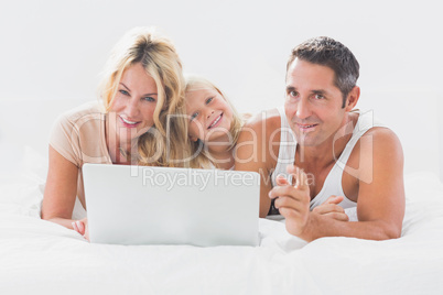 Family lying on a bed with laptop