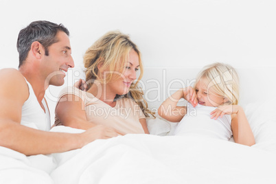 Parents looking her daughter on a bed