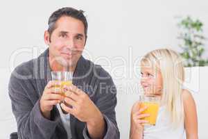 Father and daughter drinking glass of orange juice