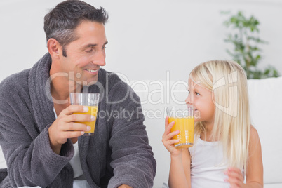 Father and his daughter drinking glass of orange juice