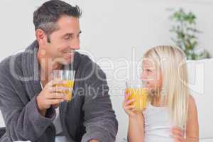 Father and his daughter drinking glass of orange juice