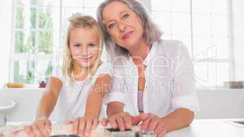 Smiling granddaughter making biscuits with her grandmother