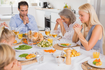 Family praying before dinner