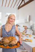 Smiling blonde woman showing the roast turkey