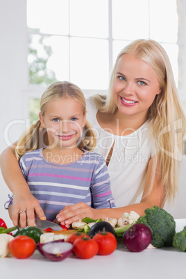 Smiling mother teaching cutting vegetables