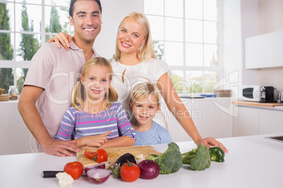 Smiling posing family cutting vegetables together