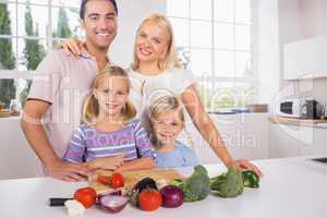 Smiling posing family cutting vegetables together