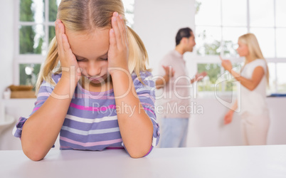 Little girl looking depressed in front of fighting parents
