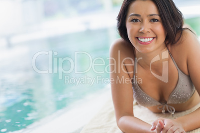 Smiling girl lying by swimming pool
