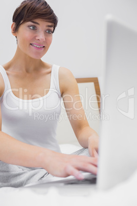 Woman in bed typing on laptop