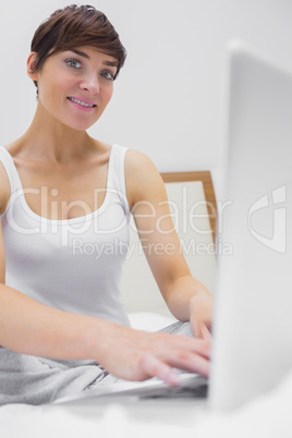 Brunette woman using laptop in bed