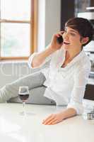 Woman phoning in kitchen with a glass of wine