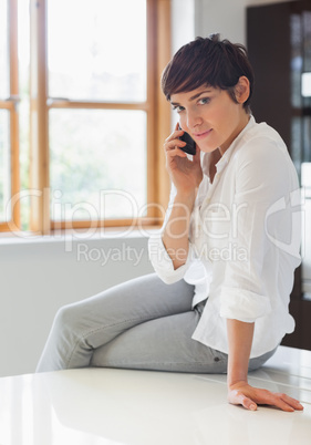 Woman sitting on worktop on the phone
