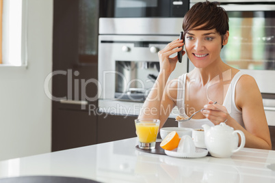 Woman talking on phone and having breakfast