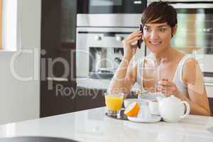 Woman talking on phone and having breakfast