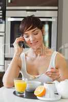 Woman eating breakfast and talking on phone
