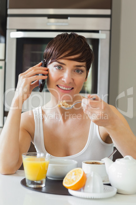 Woman eating cereal and talking on phone