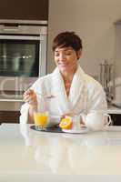 Woman in bathrobe having breakfast