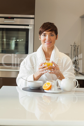 Woman in bathrobe having healthy breakfast