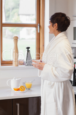 Woman looking out of window with a coffee