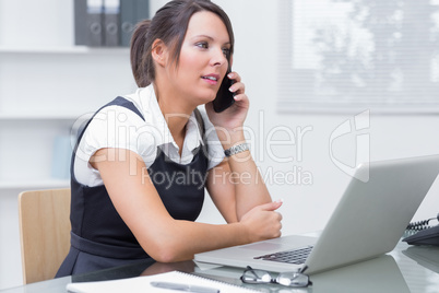 Female executive on call in front of laptop at desk