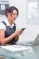 Business woman text messaging in front of laptop at office