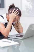 Business woman with head in hands in front of laptop at desk