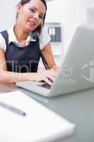 Business woman using landline phone and laptop