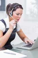 Business woman wearing headset and using laptop at desk