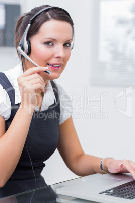 Female executive wearing headset while using laptop at desk