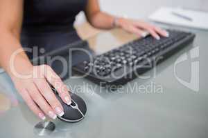 Woman using computer mouse and keyboard at desk