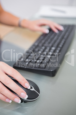 Hands using computer mouse and keyboard at office desk