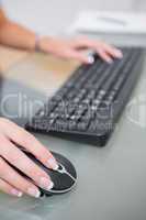Hands using computer mouse and keyboard at office desk